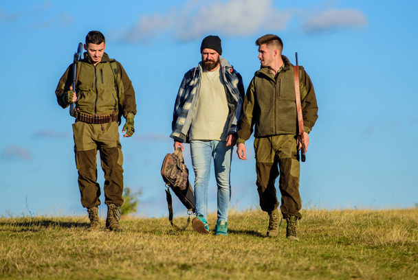 Group men hunters or gamekeepers nature background blue sky. Guys gathered for hunting. Men carry hunting rifles. Hunting as hobby and leisure. Hunters with guns walk sunny fall day. Brutal hobby - Fotoğraf, Görsel