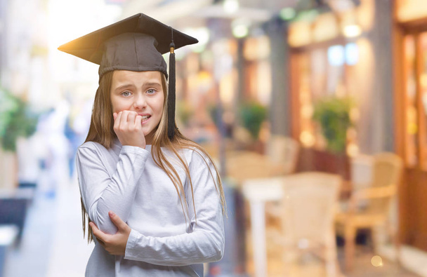 Young beautiful girl wearing graduate cap over isolated background looking stressed and nervous with hands on mouth biting nails. Anxiety problem. - Photo, Image