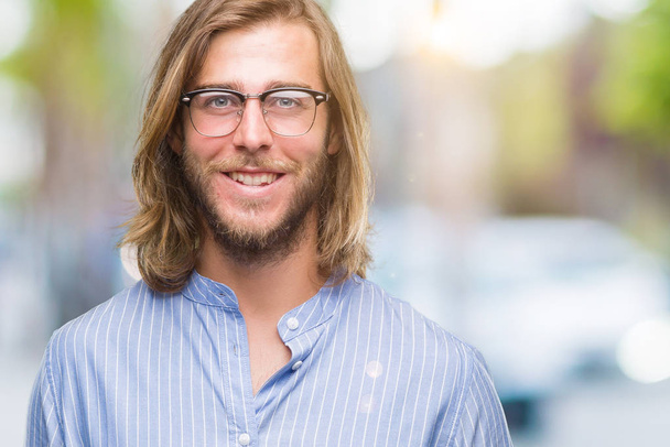 Young handsome man with long hair wearing glasses over isolated background with a happy and cool smile on face. Lucky person. - Foto, immagini