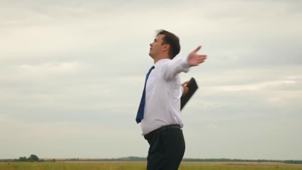 Geschäftsmann in weißem Hemd und Krawatte mit Aktentasche in der Hand jubelt und dreht sich gegen den Himmel - Filmmaterial, Video