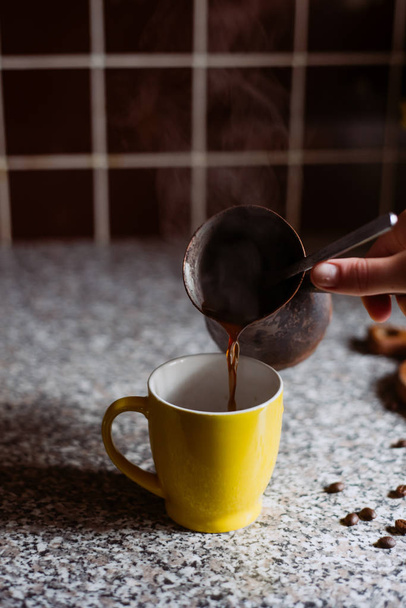 a woman pours hot coffee in the cup in the morning - Fotoğraf, Görsel