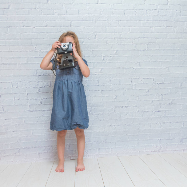 Dziewczyna, dziecko z rocznika kamery na tle ściany Cegła biała - Zdjęcie, obraz