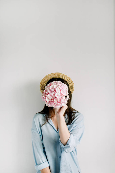 Mujer joven sostiene ramo de flores de hortensia rosa sobre fondo blanco. concepto de moda belleza floral
. - Foto, Imagen