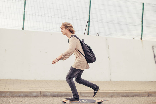 boy riding longboard on boardwalk, warm summer time - Zdjęcie, obraz