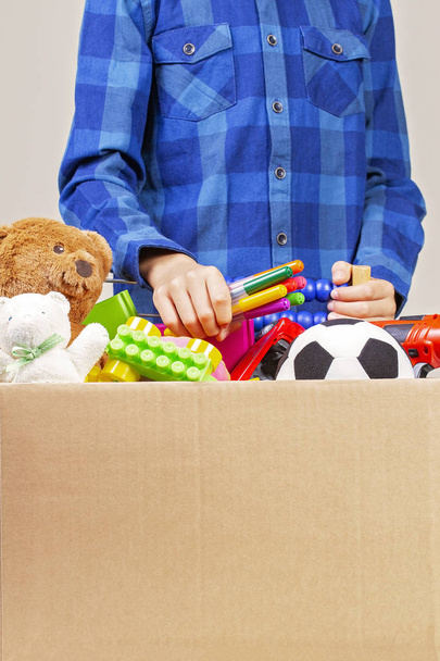 Concept de don. Enfant avec boîte de don avec vêtements, livres, fournitures scolaires et jouets
 - Photo, image