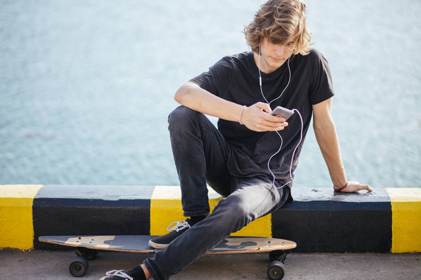hipster hombre sentado en longboard usando su teléfono
 - Foto, imagen