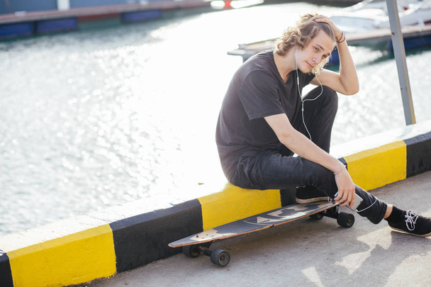 hipster man sitting on longboard using his phone - Fotó, kép