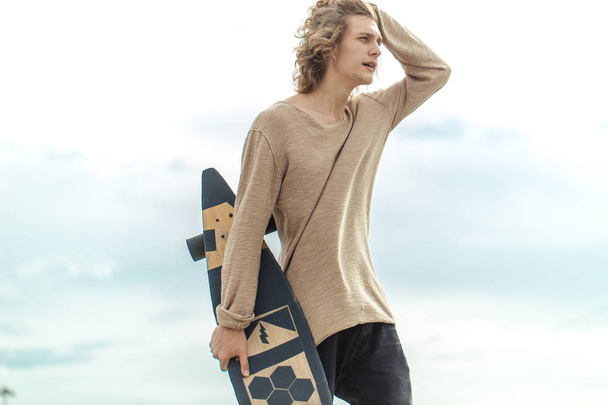 Stylish man stands on street and hold long board in hands - Foto, Imagen