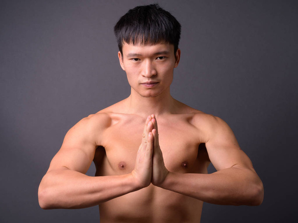 Young shirtless Chinese man against gray background - Photo, Image