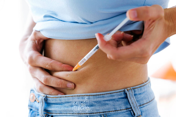 Female diabetes patient making subcutaneous insulin injection into her abdomen. Diabetes, health care and medical concept.  - Photo, Image