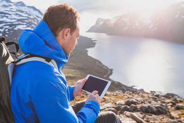 traveler backpacker using digital tablet computer outside in mountains, mobile travel application online - Foto, immagini