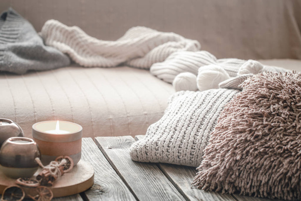 Stillleben von zu Hause aus auf einem hölzernen Hintergrund mit Kerze und Kissen, Wohnkomfort-Konzept - Foto, Bild