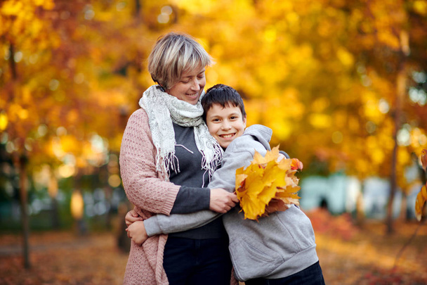 Мати і син знаходяться в осінньому міському парку. Батьки позують, посміхаються, грають і розважаються. Яскраві жовті дерева
. - Фото, зображення