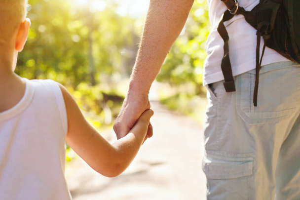 child holding hand of adult parent outside in summer park - Foto, Imagen