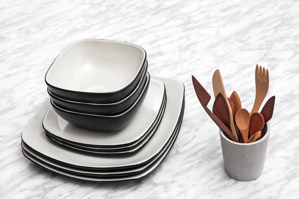 Ceramic plates and wooden utensils on marble background. - Фото, изображение