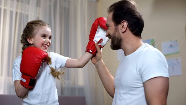 Happy daughter boxing with bearded father at home, sport childhood and hobby - Φωτογραφία, εικόνα
