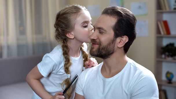 Beautiful daughter kissing father cheek and combing his hair playing hairdresser - Foto, Imagen