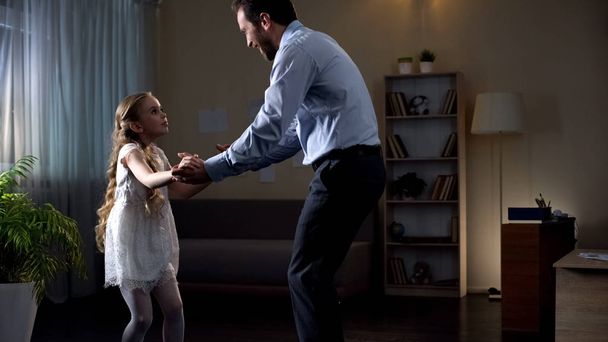 Father moving to music at home, inviting daughter to dance, having fun together - Foto, Bild