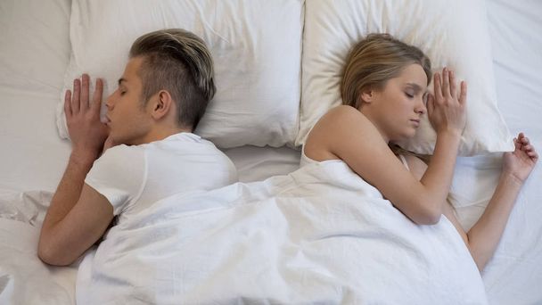 Man and woman quietly sleeping, lying back to back in bed, couple relationship - Zdjęcie, obraz
