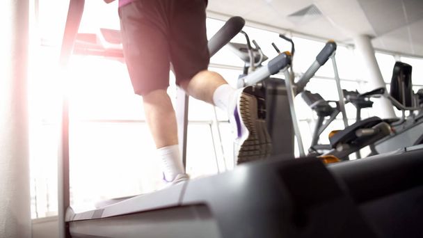 Person running on treadmill, cardio exercise, warming up before muscles training - Foto, Imagem