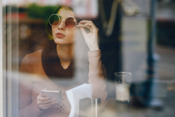 brunette girl using phone while at a restaurant - Foto, Bild