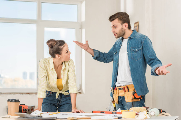 emotivo giovane uomo gesticolando e litigando con la fidanzata mentre discuteva di riparazione a casa
 - Foto, immagini