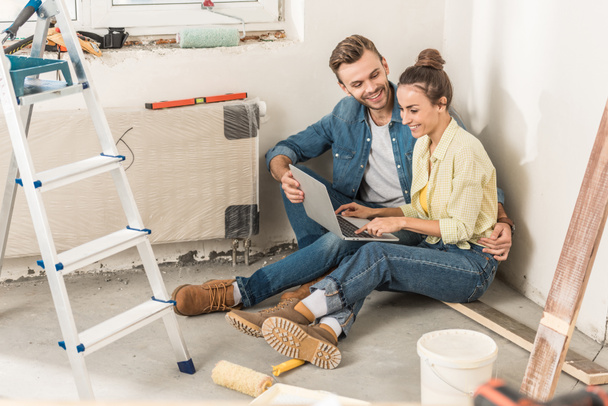 happy young couple using laptop during renovation in new house  - Photo, Image