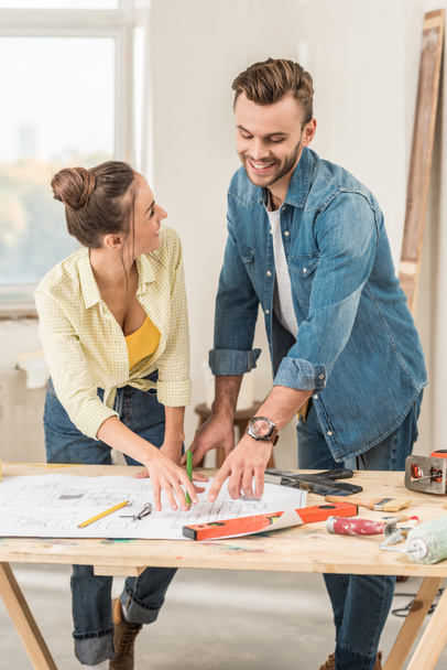 happy young couple discussing blueprint during renovation - Фото, зображення