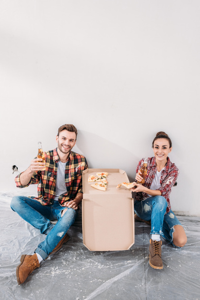 Szczęśliwa Młoda para jedzenie pizzy i picia piwa podczas przerwy w regulacyjno-rozruchowe - Zdjęcie, obraz