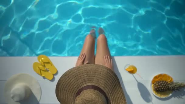 Sexy woman in hat sitting on poolside and enjoying summer vacation at resort - 映像、動画