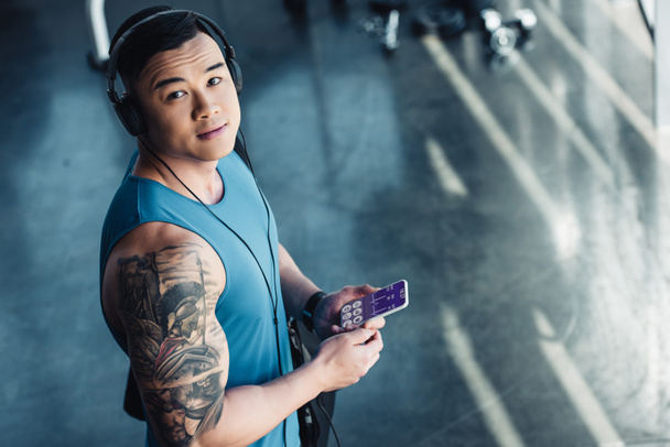 young asian sportsman using smartphone with health data appliance and listening to music  - 写真・画像