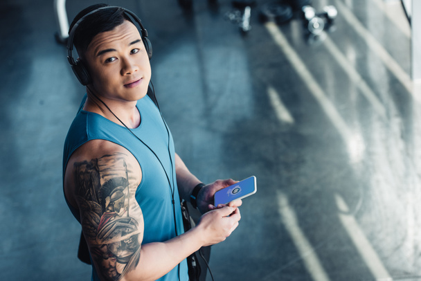 молодий азіатський спортсмен використовує смартфон і слухає музику
  - Фото, зображення