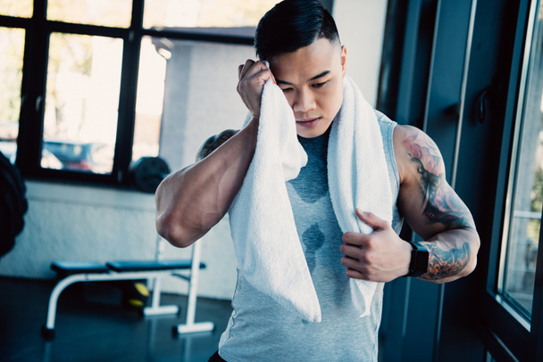 giovane asiatico sportsman wiping faccia con asciugamano dopo lungo allenamento
 - Foto, immagini