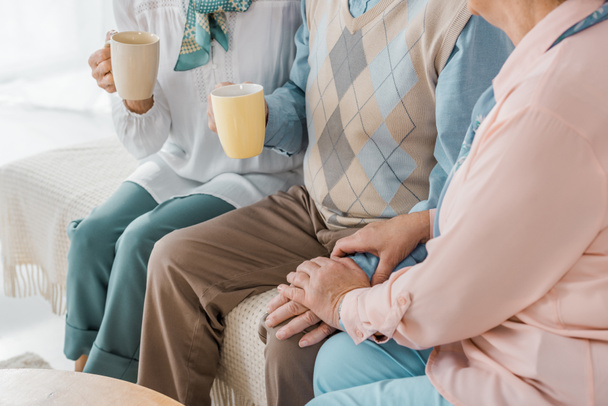 close up de pessoas idosas sentadas no sofá e bebendo chá juntos
 - Foto, Imagem