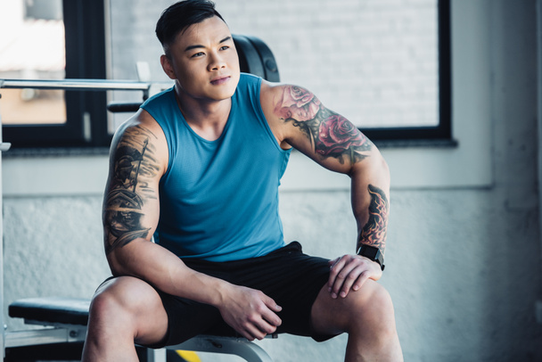 muscular asian young sportsman sitting at gym  - Фото, зображення