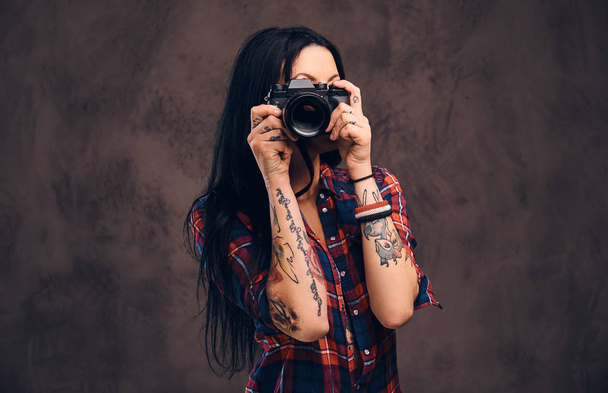 Tatuażem dziewczyna biorąc zdjęcie patrząc na kamery w studio. - Zdjęcie, obraz