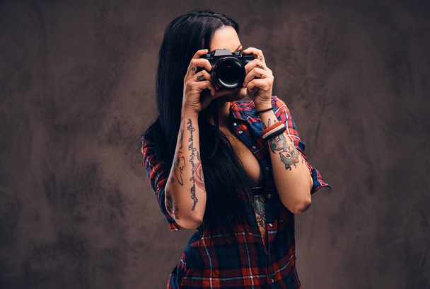 Τατουάζ κορίτσι παίρνει μια φωτογραφία που βλέπουν φωτογραφική μηχανή σε ένα στούντιο. - Φωτογραφία, εικόνα