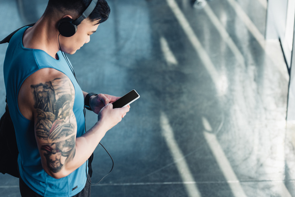 young sportsman using smartphone and listening to music  - Foto, Bild