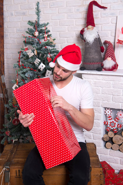 online christmas shopping. New year scene with tree and gifts. delivery christmas gifts. man in santa hat hold christmas present. happy santa man. The morning before Xmas. Christmas fun. - Φωτογραφία, εικόνα