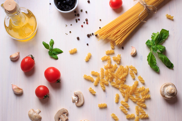 Top view of traditional ingredients for italian pasta on white table. Pasta, tomatoes, green basil, olive oil, mushrooms and garlic - Fotoğraf, Görsel