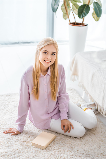 young beautiful woman sitting on carpet with book at home - Foto, afbeelding