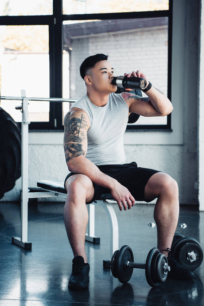 jovem asiático desportista beber água no ginásio
  - Foto, Imagem