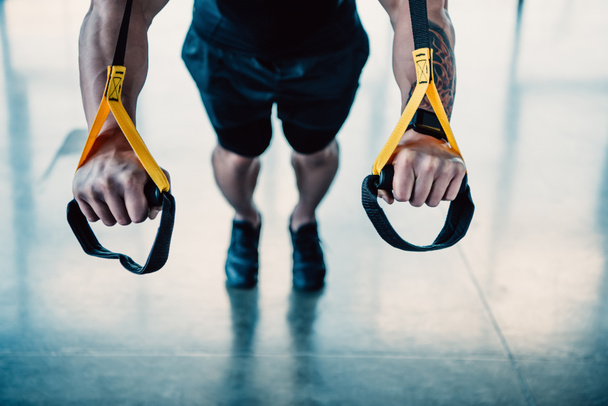 обрезанный вид тренировки молодых мускулистых спортсменов с полосами сопротивления в тренажерном зале
 - Фото, изображение