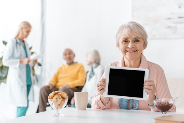 Starší žena ukazuje černou obrazovku na digitálním tabletu v nemocnici - Fotografie, Obrázek