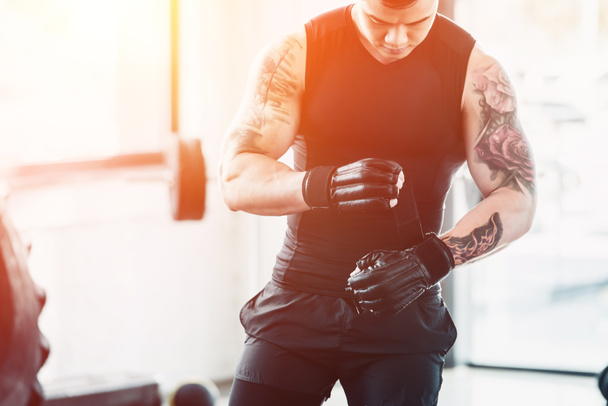 Nézd a fiatal sportoló viselése boksz-kesztyűket edzőteremben napfény vágott - Fotó, kép