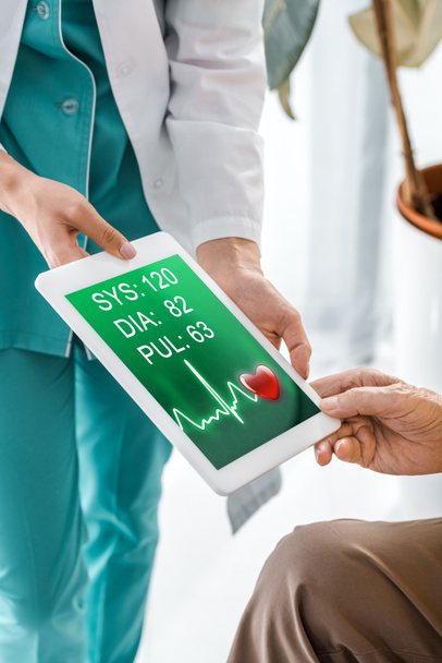 vicino al medico e alle mani del paziente che tengono la compressa digitale con cardiogramma sullo schermo
 - Foto, immagini