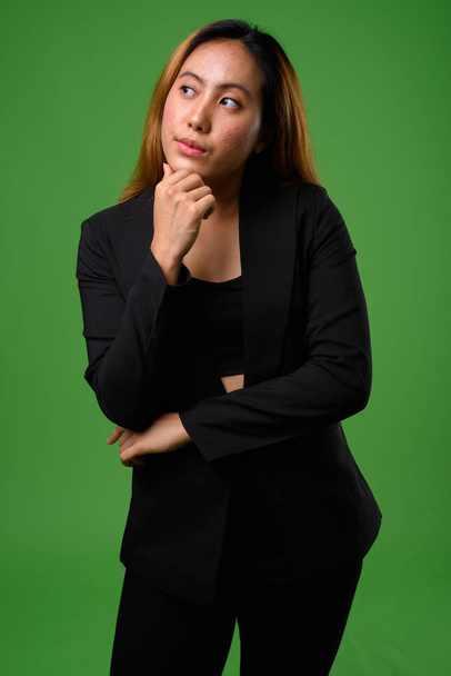 Portrait of young Asian businesswoman against green background - Foto, Imagen