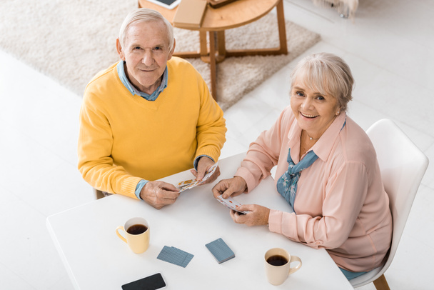 happy smiling senior couple playing cards at table at nursing home - Foto, Imagem