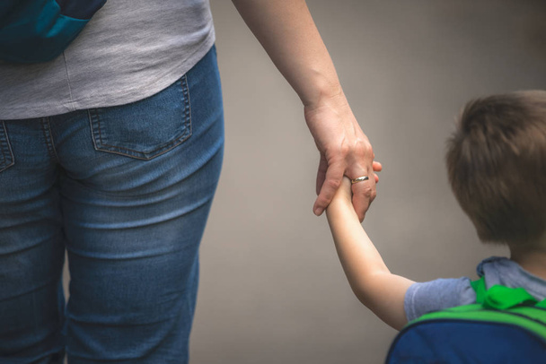 Pequeno menino caucasiano de mãos dadas e caminhando junto com sua mãe
 - Foto, Imagem