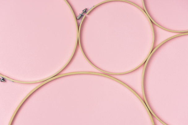 flat lay with wooden embroidery hoops arranged on pink background - Photo, Image